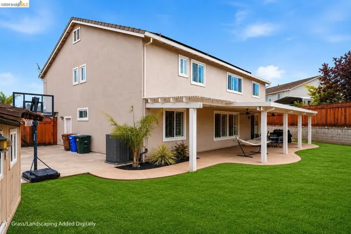 Expansive backyard featuring a manicured lawn, a large concrete patio, and a covered pergola