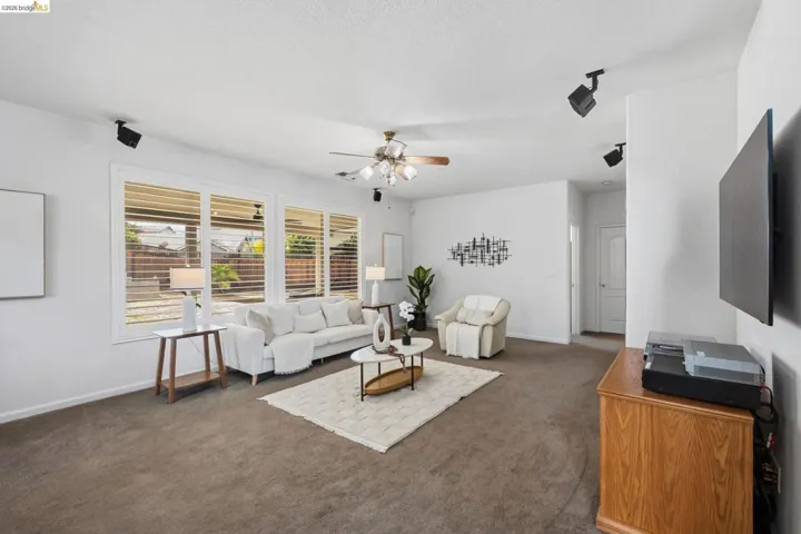Spacious living area featuring brown carpeting, white walls, and track lighting