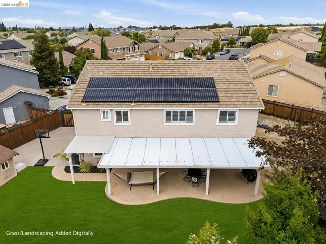 Rear exterior featuring a full-width covered patio with a solid roof, a manicured lawn, and solar panels