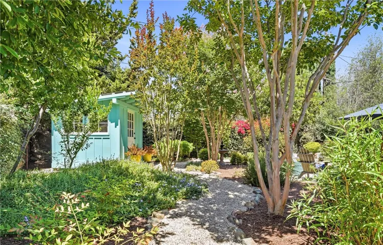 And what a backyard! Meandering gravel paths lead past a garden shed, sitting area, bird bath, raised beds, dining patio, and lush low water use landscaping.