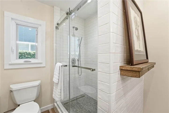 The first thing you see when you enter the hall bathroom is a shelf with wood sourced from a barn in New Hampshire. Check out the lovely tile work behind the gliding shower door.