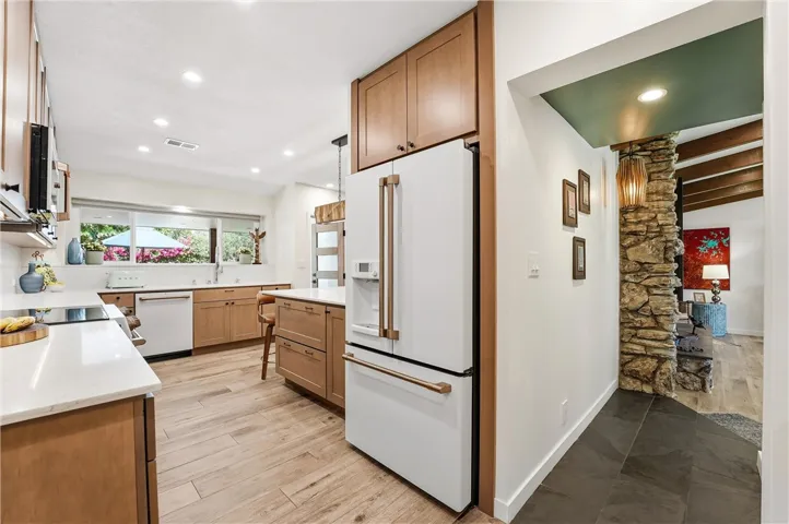 The GE Café Series appliances, with its rose gold handles, blend with the wood cabinets and porcelain flooring.
