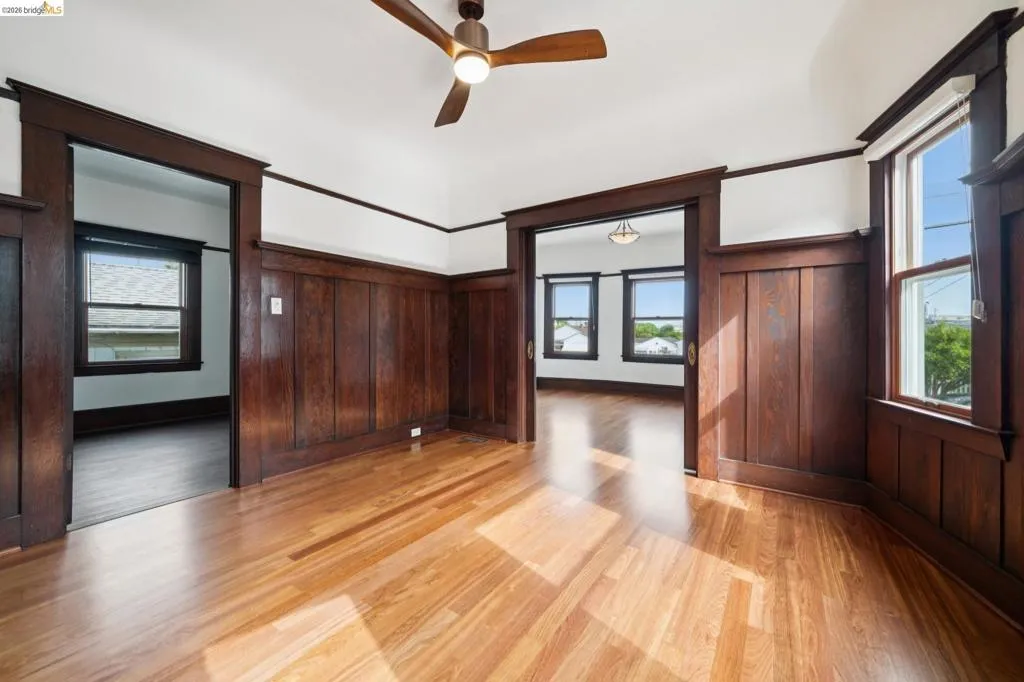 Room featuring wood-finish flooring, dark wood wainscoting, and white walls