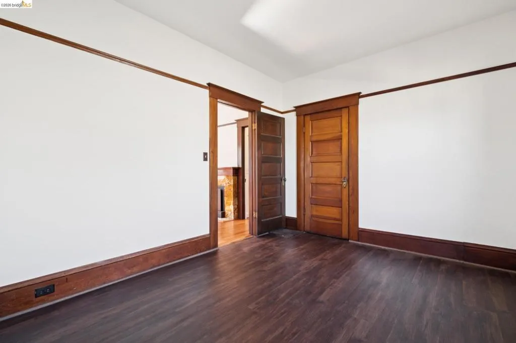 Interior room featuring dark wood-finish flooring, white walls, and rich wood trim