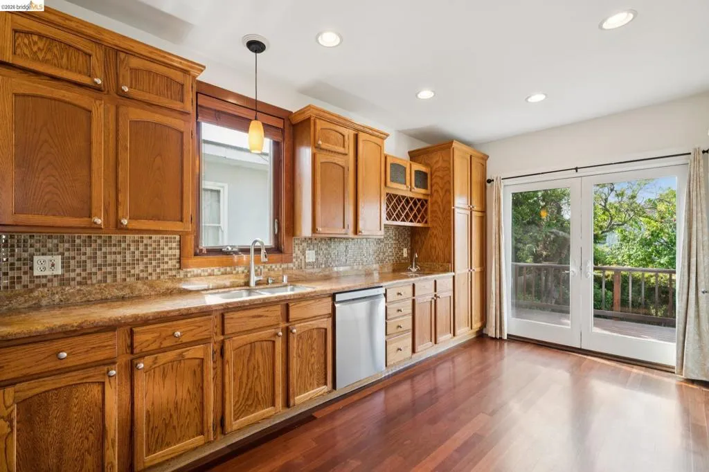 Kitchen featuring wood-finish cabinetry, stainless steel dishwasher, and mosaic tile backsplash