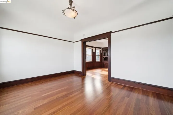 Hardwood flooring throughout, framed by dark wood baseboards and picture rail molding