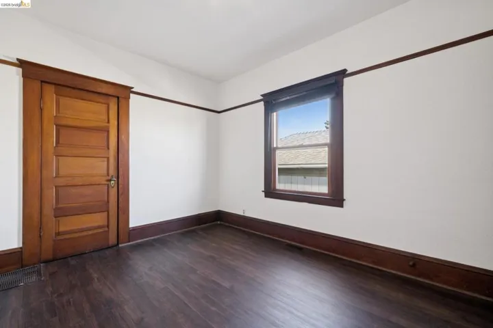 Interior room featuring a wood-finish floor, white walls, and dark wood trim