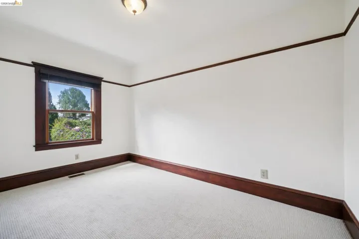 Carpeted room with a single window featuring dark wood trim, baseboards, and a picture rail molding