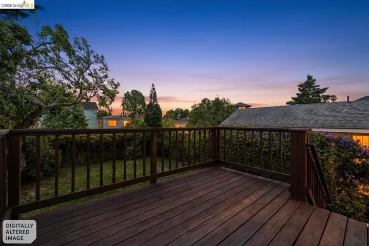 Spacious wood deck with a full-height railing overlooking a lush green yard and mature landscaping