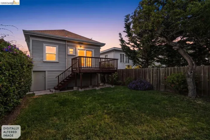 Spacious backyard featuring a wooden privacy fence, mature trees, and a manicured lawn