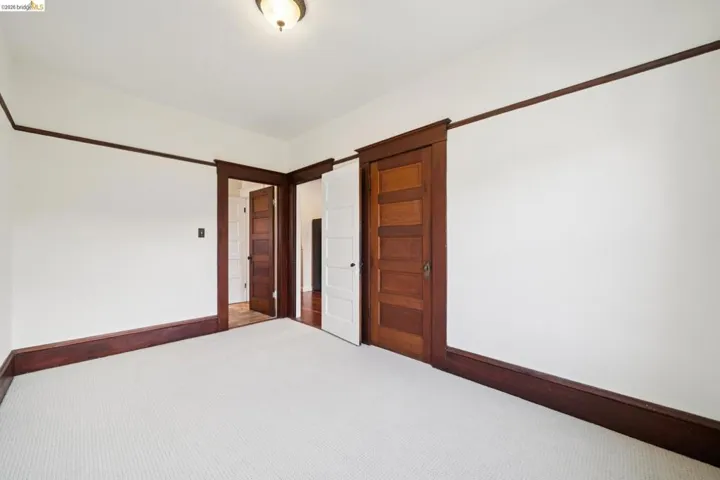 Carpeted interior space with contrasting dark wood trim and white walls