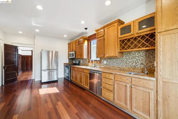 Open-concept kitchen featuring wood-finish flooring, recessed lighting, and a mosaic tile backsplash