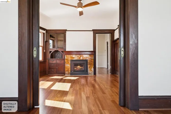 Hardwood flooring throughout featuring a built-in fireplace with a stone surround and a built-in wooden cabinet with glass doors