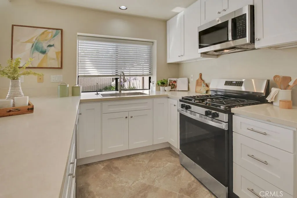 Beautifully remodeled kitchen featuring quartz countertops, white shaker cabinetry, stainless steel appliances, recessed lighting, and abundant workspace.