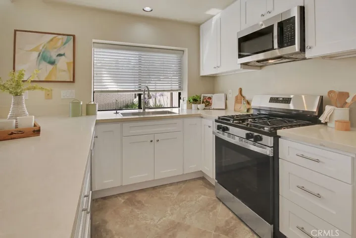 Beautifully remodeled kitchen featuring quartz countertops, white shaker cabinetry, stainless steel appliances, recessed lighting, and abundant workspace.