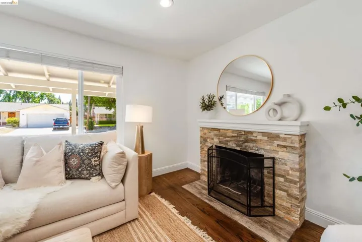 Living area featuring rich wood-finish flooring and a stone-clad fireplace with a classic mantel