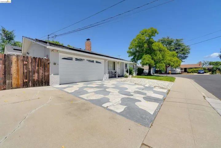 Single-story residence featuring a white garage door with decorative windows, a brick chimney, and solar panels