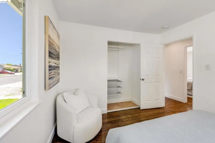 Bedroom featuring wood-finish flooring, white walls, and a window with white trim