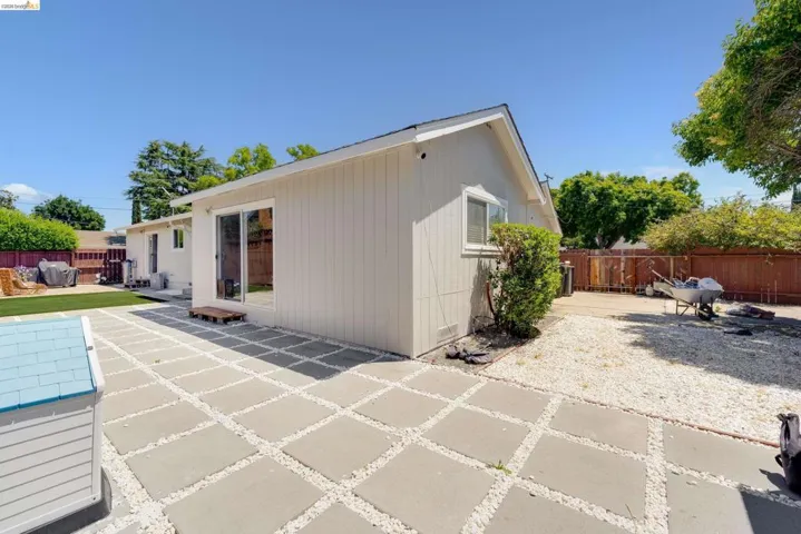 Expansive backyard featuring a concrete paver patio with gravel infill, a sliding glass door entry, and a white gravel area