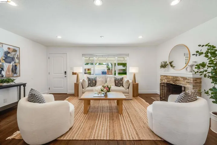 Living area featuring rich wood-finish flooring and a stone-clad fireplace with a hearth