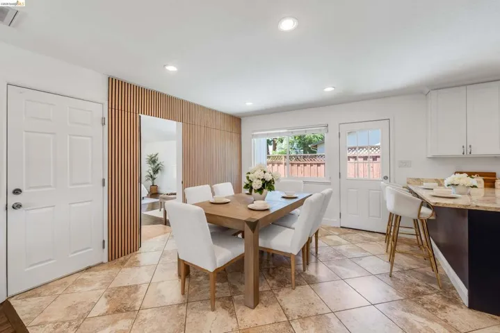 Dining area featuring tile flooring, a wood-slat accent wall, recessed lighting, and a window with outdoor views