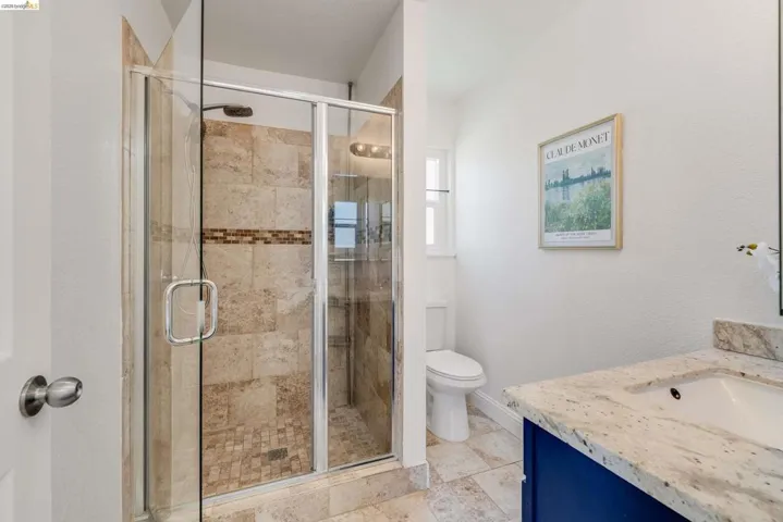 Glass-enclosed shower with tiled walls and a decorative mosaic band