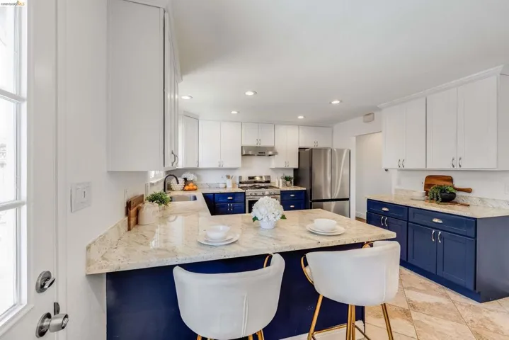 Kitchen featuring a peninsula with seating, granite countertops, two-tone cabinetry, stainless steel appliances, and recessed lighting