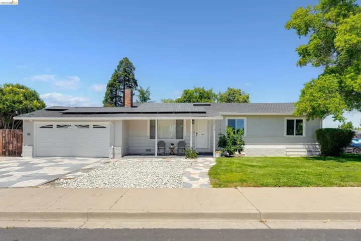 Ranch-style residence featuring a gray exterior, a two-car garage with white paneled doors, and a front yard with a manicured lawn