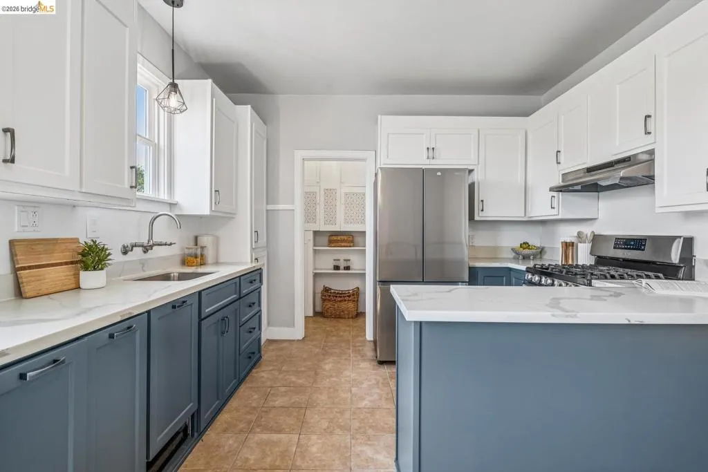 Kitchen features two-tone cabinetry, stone countertops, stainless steel appliances, and a walk-in pantry.