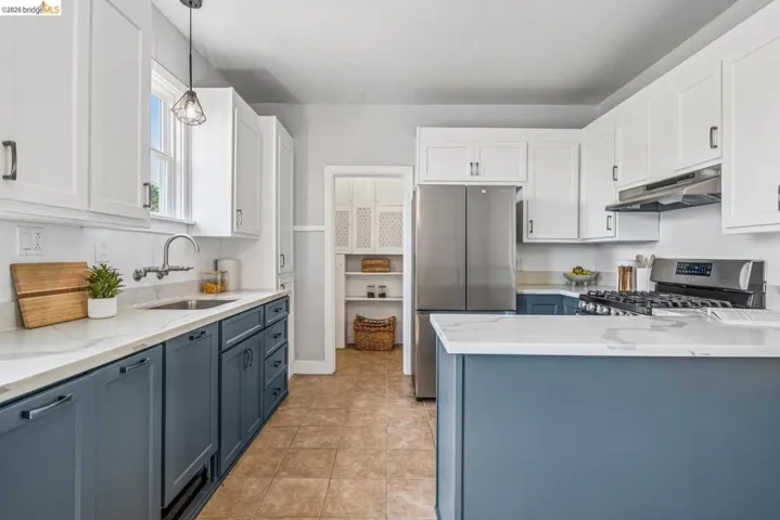 Kitchen features two-tone cabinetry, stone countertops, stainless steel appliances, and a walk-in pantry.