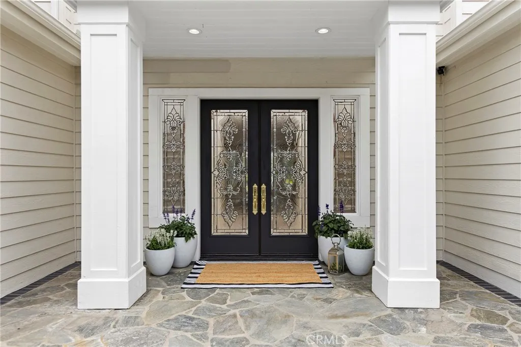 Beveled glass double door entryway featuring stone flooring, and vibrant potted plants for added curb appeal.