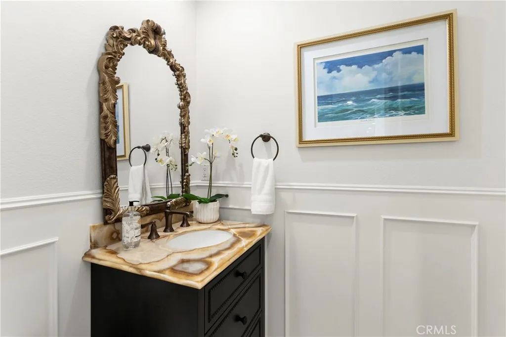 Downstairs Guest Bath-This inviting bathroom features a unique stone vanity , custom wainscoting and coastal-themed artwork, enhancing its modern appeal.