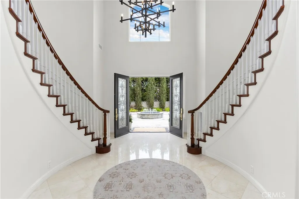 Welcome to this striking foyer featuring a grand staircase and inviting double front doors that open to scenic views.