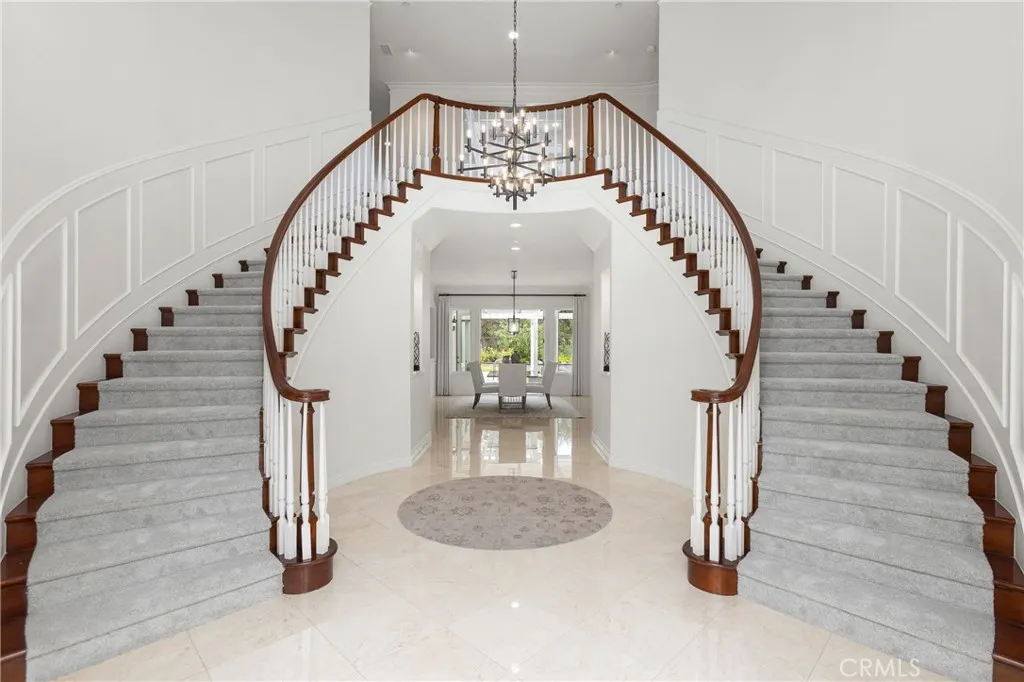Grand foyer with dual staircases and a modern chandelier, creating an impressive first impression