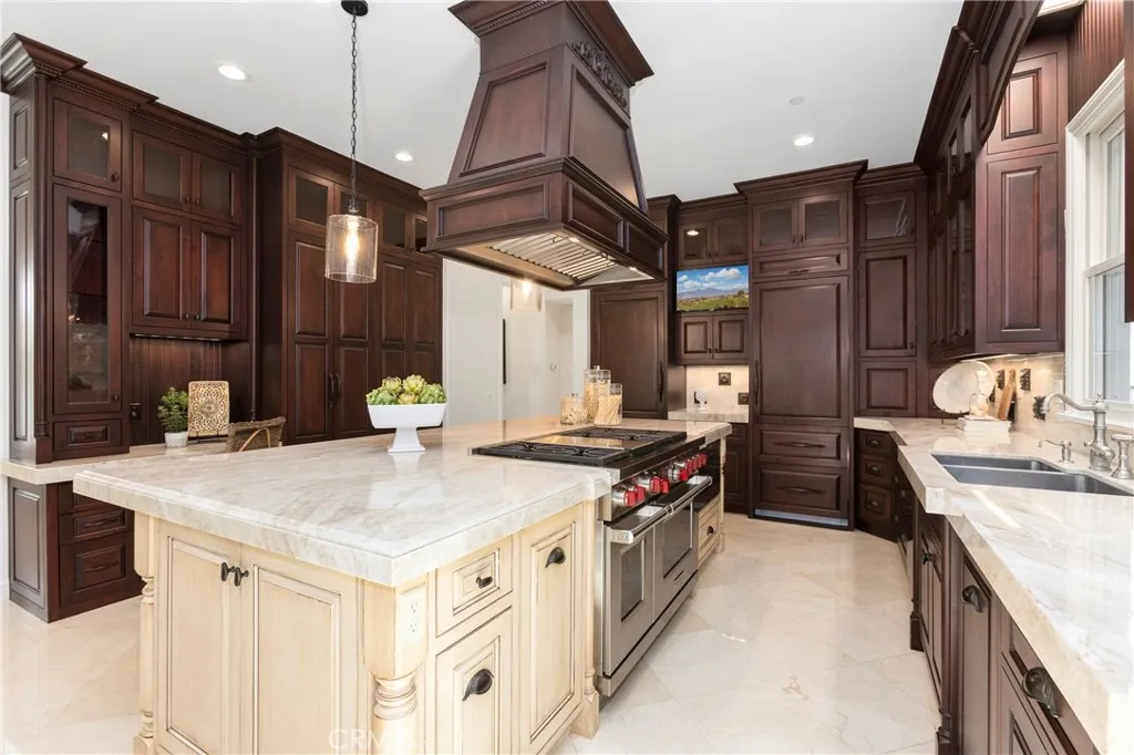 This gourmet kitchen features rich wood cabinetry, a spacious island, and premium appliances for culinary enthusiasts. 6 Burner Wolf Range with double ovens and griddle, 2 Bosch dishwashers, double sub zero fridges with 4 pull out freezer drawers, Wolf pull out microwave, tons of upgraded cabinets it pull out drawers, and so much more