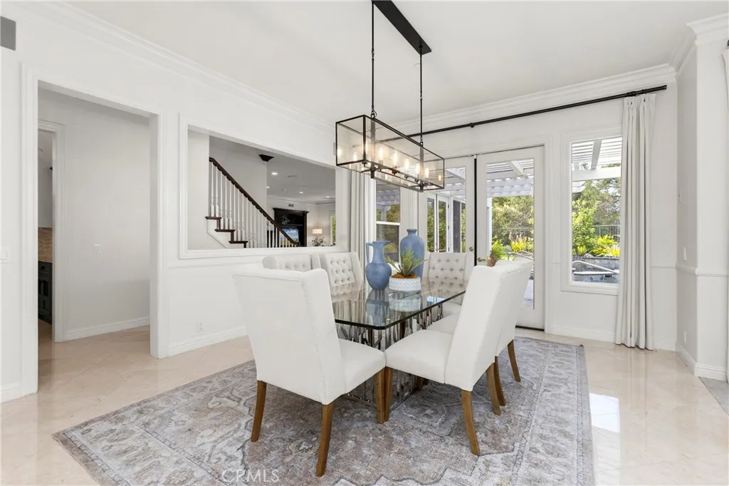 Bright dining area featuring large windows, modern lighting, and access to an outdoor patio space.