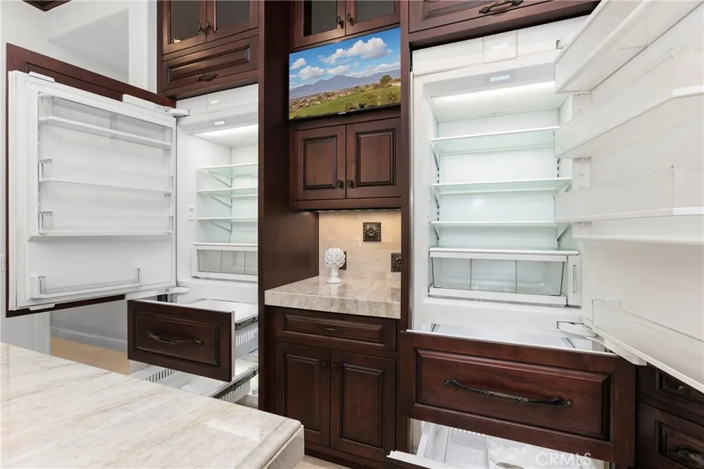 This gourmet kitchen features dual  Sub Zero refrigerators, 4 pull out freezer drawers with ample storage, fun appliance garage and modern finishes for culinary enthusiasts.