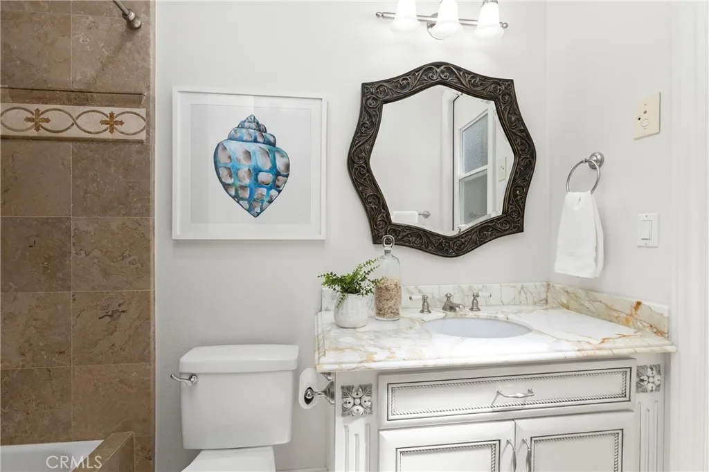 En-Suite Bathroom for Bedroom 1 
Bright bathroom featuring a decorative mirror, modern fixtures, and unique artwork, enhancing its inviting atmosphere and private direct access door to backyard