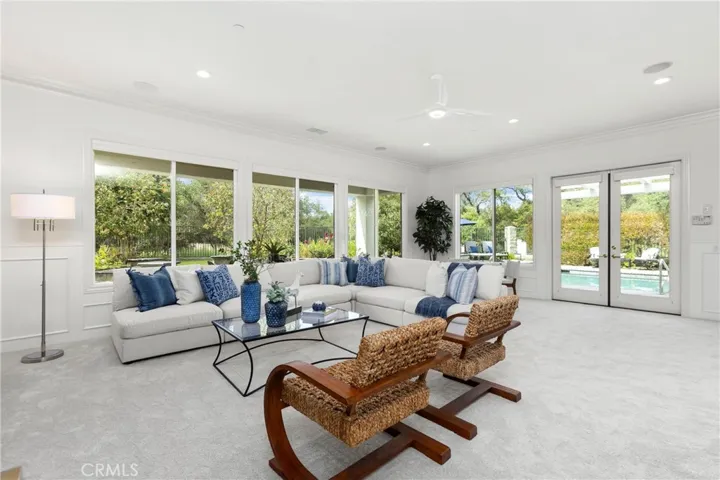 Spacious living area with large windows, offering abundant natural light and direct views of the pool.
