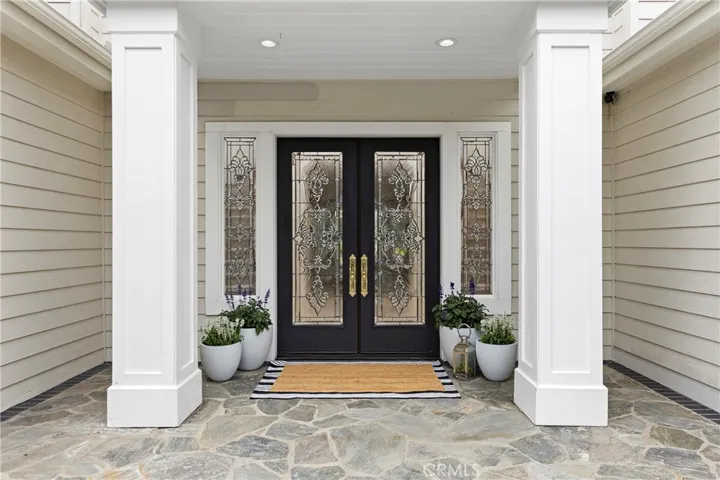 Beveled glass double door entryway featuring stone flooring, and vibrant potted plants for added curb appeal.