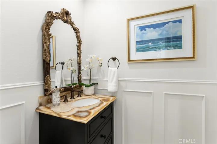 Downstairs Guest Bath-This inviting bathroom features a unique stone vanity , custom wainscoting and coastal-themed artwork, enhancing its modern appeal.
