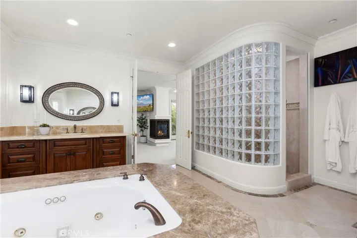 Primary Bathroom-Luxurious bathroom featuring a jetted tub, modern glass block shower, and ample natural light.