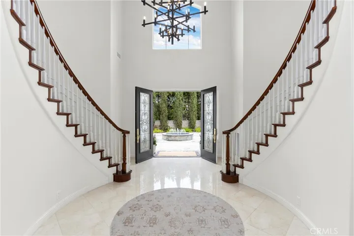 Welcome to this striking foyer featuring a grand staircase and inviting double front doors that open to scenic views.