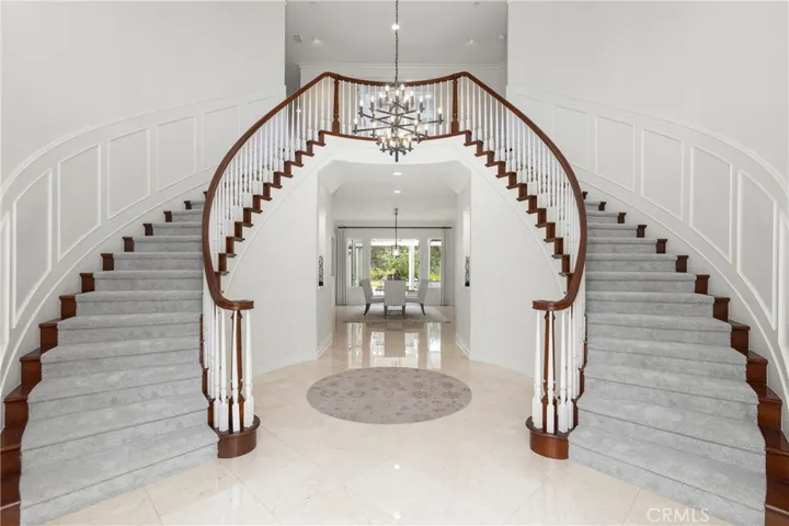 Grand foyer with dual staircases and a modern chandelier, creating an impressive first impression