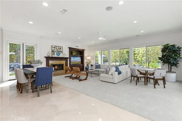 flooded with abundant natural light, showcasing a cozy fireplace and open connectivity to dining spaces.
