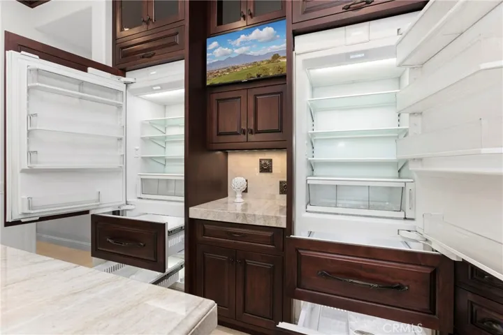 This gourmet kitchen features dual  Sub Zero refrigerators, 4 pull out freezer drawers with ample storage, fun appliance garage and modern finishes for culinary enthusiasts.
