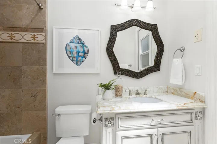 En-Suite Bathroom for Bedroom 1 
Bright bathroom featuring a decorative mirror, modern fixtures, and unique artwork, enhancing its inviting atmosphere and private direct access door to backyard