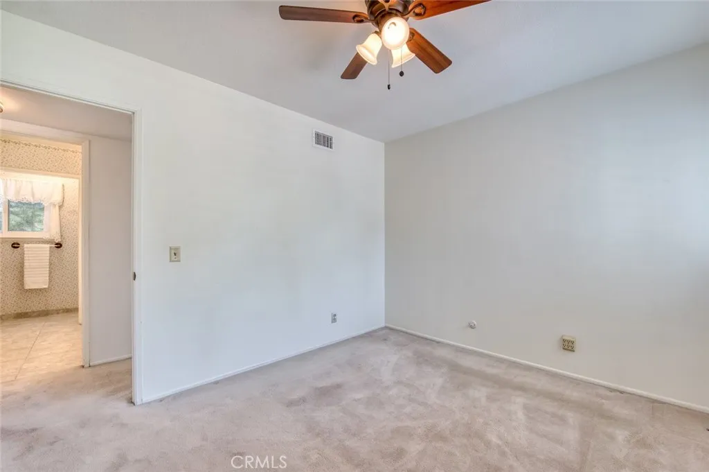 Main floor bedroom with ceiling fan and adjacent bathroom.