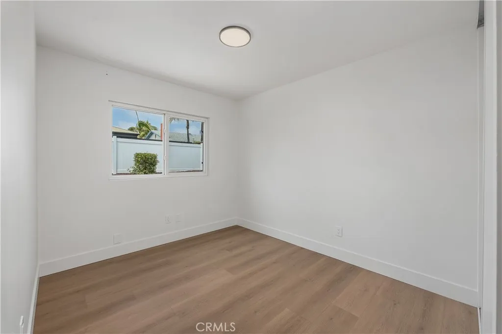 Secondary bedroom number two featuring luxury vinyl plank (LVP) flooring and modern baseboards, accented with sleek black finishes in the lighting, door hardware for a clean, contemporary feel.