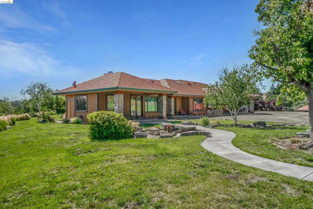 Single-story residence featuring a terracotta tile roof, earth-toned stucco siding, and stone accents